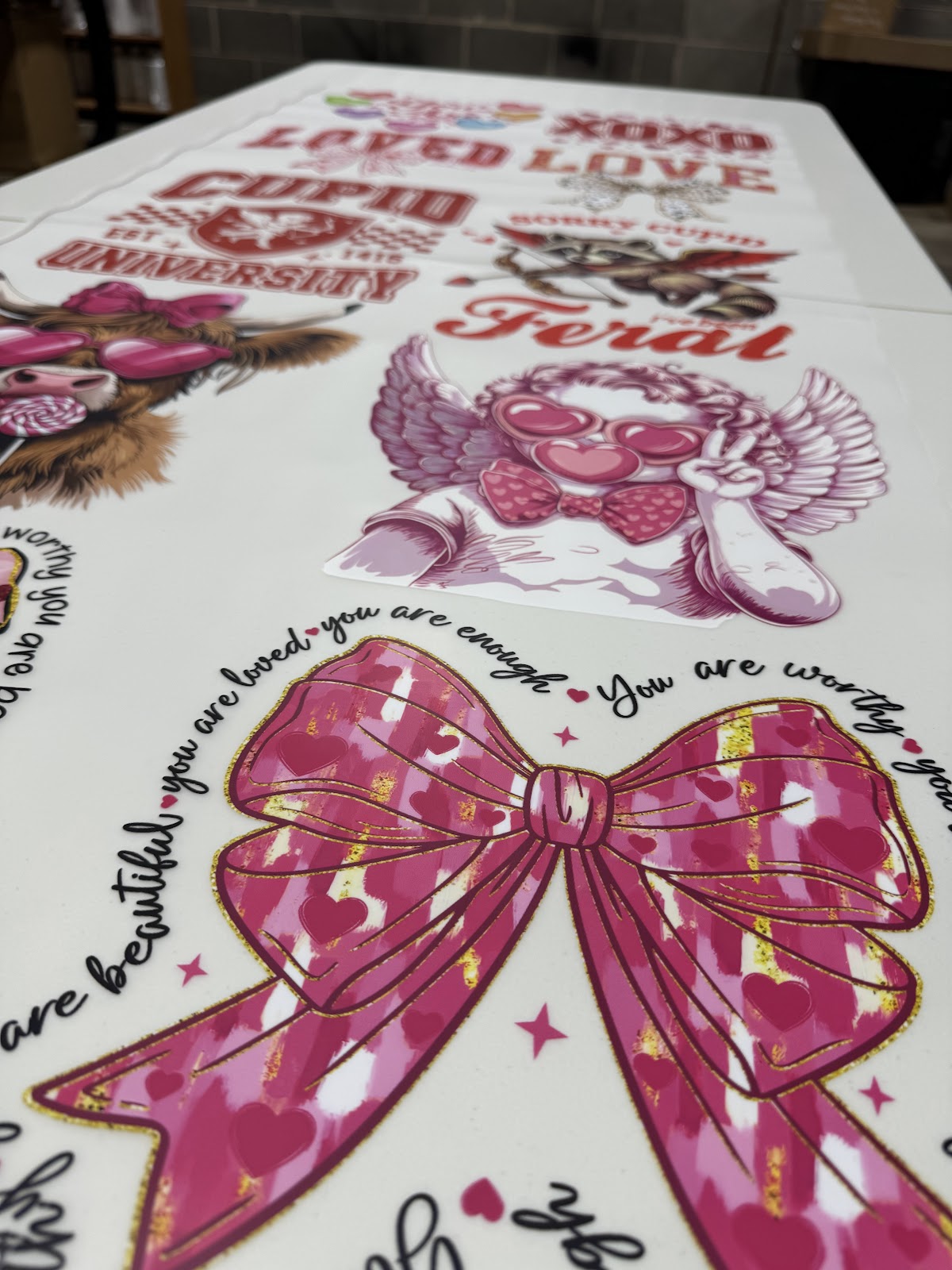 Freshly printed DTF gang sheet transfers on the production table